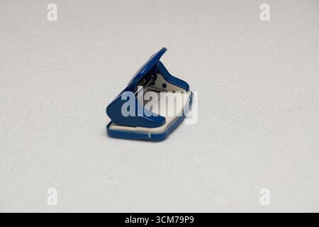 A blue stapler on a white textured surface Stock Photo