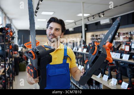 A man is standing in a store holding a chainsaw tool Stock Photo