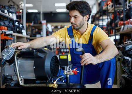 A man worker is diligently working on an air compressor in a store setting Stock Photo
