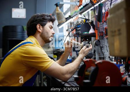 Service man repairing a broken power drill inside a busy workshop Stock Photo