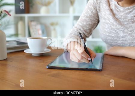 Close up portrait of a woman hand handwriting using pen on a digital tablet Stock Photo