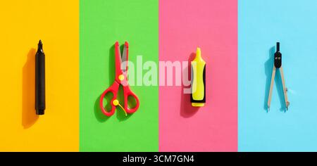 Black marker, red scissors, yellow highlighter and compass arranged on colorful background creating vibrant and playful composition, ideal for educati Stock Photo