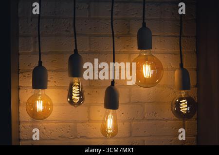 Vintage-style light bulbs hanging against a white background,. Decor Stock Photo