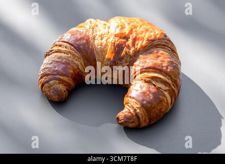 freshly baked breakfast croissant on sunny grey table Stock Photo