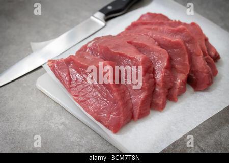 fresh raw sliced beef meat on grey kitchen table Stock Photo
