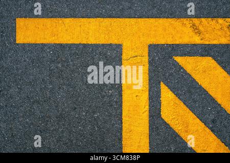 Geometric yellow lines painted on asphalt road, abstract urban pattern background. Top view. Stock Photo