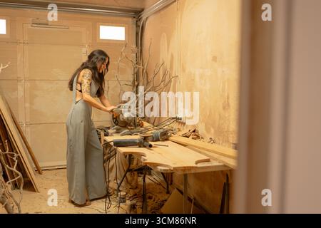 Carpenter using circular saw cutting wood plank in workshop Stock Photo