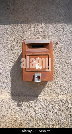Vintage rusty metal mailbox fixed to rough plastered wall outdoors Stock Photo
