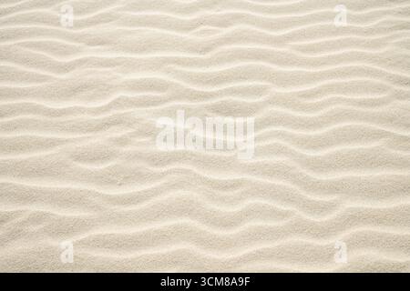 Light beige sand with wavy drifts. Natural surface as a background. Stock Photo