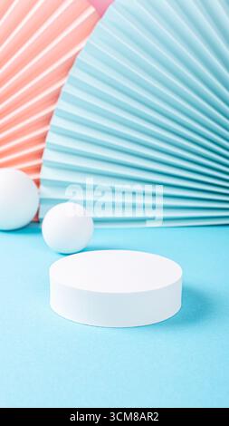 Circular white pedestal placed on blue surface, surrounded by colorful paper fans and spheres, creating a playful and modern display, stories template Stock Photo
