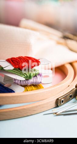 Vibrant embroidery threads are neatly arranged in a wooden hoop, accompanied by sewing needles and soft fabric, creating a cozy crafting atmosphere, p Stock Photo