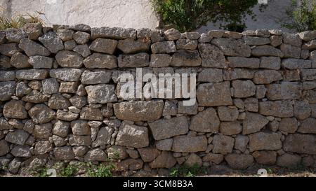 Rustic stone wall with multicolored natural rocks and mortar Stock Photo