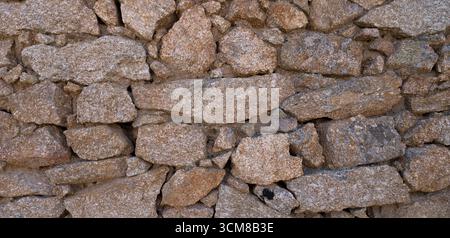Rustic stone wall with multicolored natural rocks and mortar Stock Photo