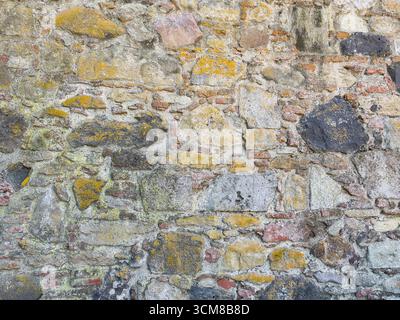 Rustic stone wall with multicolored natural rocks and mortar Stock Photo