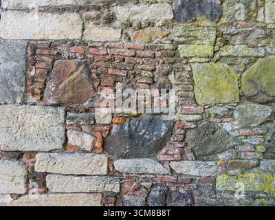 Rustic stone wall with multicolored natural rocks and mortar Stock Photo