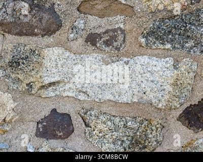 Rustic stone wall with multicolored natural rocks and mortar Stock Photo