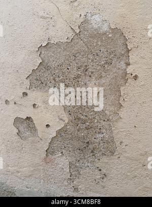 Close-up of a deteriorating plaster wall showing cracks, peeling layers, and exposed brick Stock Photo