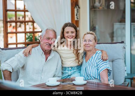 Smiling elderly couple enjoying coffee together in the garden, sharing joyful moment. Stock Photo