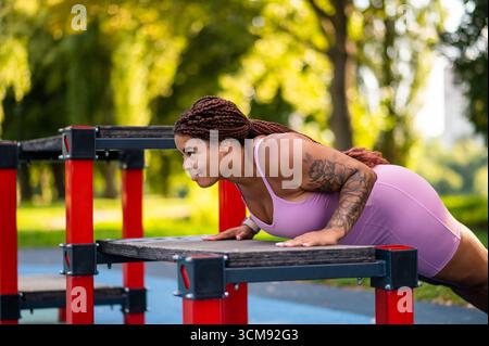 Plus size African American woman in pink sportswear doing push ups Stock Photo
