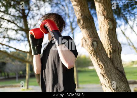 Young man wearing boxing gloves practicing in park Stock Photo