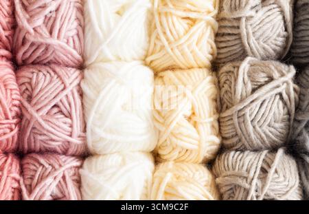 Clews of threads for knitting of different colors are stacked on the shelves, close-up. Stock Photo