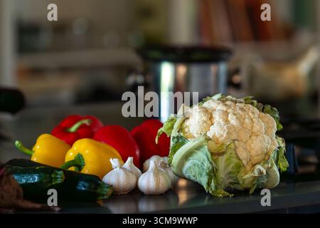 Assortment of fresh vegetables on a kitchen table. Colorful vegetables display includes zucchini, peppers, garlic and cauliflower. Stock Photo