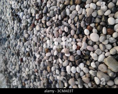 Pile of rocks with some of them being black. The rocks are scattered all over the ground Stock Photo
