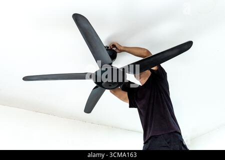 A man installing a ceiling fan. Home improvement, professional work, and technical skill concept. Stock Photo