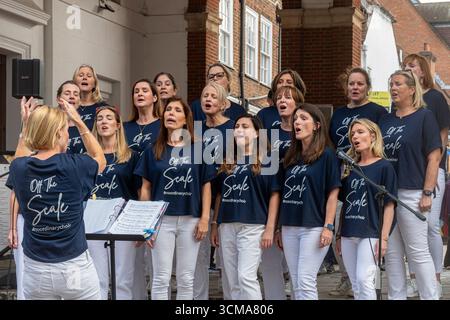 Off The Scale, women's contemporary choir performing singing in Tunsgate Quarter of Guildford town centre, Surrey, England, UK Stock Photo