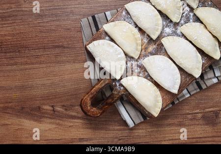 Traditional Polish dish, dumplings, raw, frozen, on a cutting board, wooden table, top view, no people Stock Photo