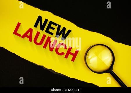 New Launch text on yellow with black paper torn ripped and magnifying glass Stock Photo