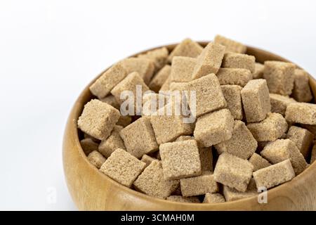 An organic brown sugar cubes in wooden bowl isolated on white background natural sweetener healthy ingredient rustic kitchen close up food concept cle Stock Photo