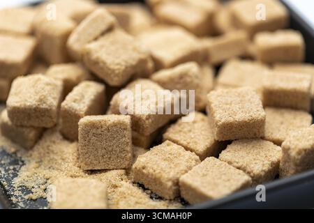 An organic brown sugar cubes in black bowl close up natural sweetener textured surface healthy ingredient rustic kitchen soft focus delicious and invi Stock Photo