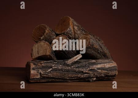 Pile of cut firewood on wooden table against brown background, closeup Stock Photo