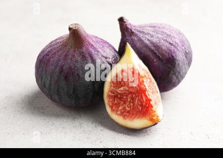 Whole and cut figs on gray textured table, closeup Stock Photo