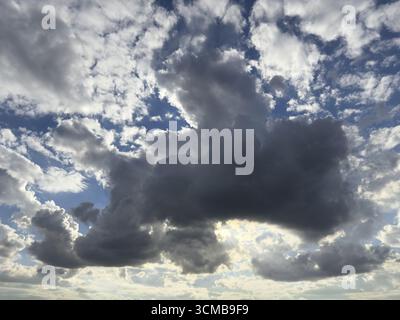 In the centre of the picture large dark cloud Cumulonimbus cloud Thunderclouds announce rain above many altocumulus clouds Cirrocumulus clouds under b Stock Photo