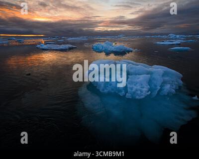 Colorful sunset reflecting on floating ice in arctic sea, Disko Bay, Greenland Stock Photo