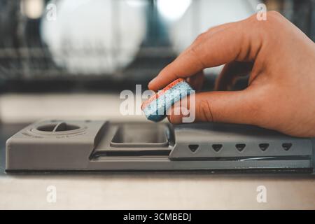 Dishwasher capsule, dishwasher tablets woman puts the capsule in the dishwasher. Stock Photo