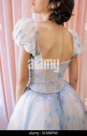 A young woman showcases a beautiful vintage dress with puffed sleeves in a softly lit room. Stock Photo