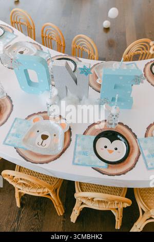 A colorful table set up for a first birthday party featuring animal-themed decorations and playful plates for guests. Stock Photo