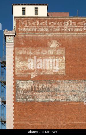 Ghost signs on a building in downtown Long Beach, California. The old signs are still partially visible on the brickwork. Stock Photo