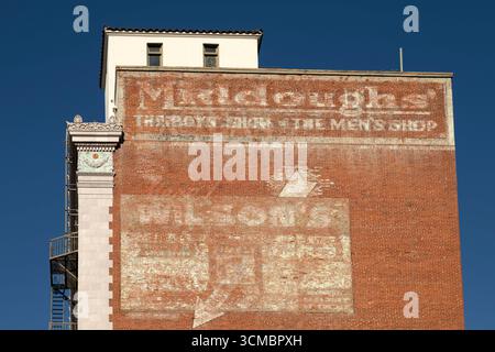 Ghost signs on a building in downtown Long Beach, California. The old signs are still partially visible on the brickwork. Stock Photo