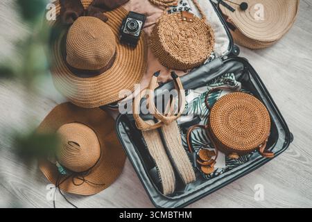 Vacation and travel concept. Suitcase, hat, bag and sunglasses on wooden floor. Stock Photo