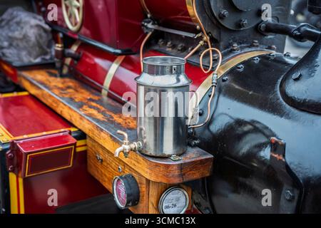 Steam engine close-up showing brass oil can, red and black paint, and wooden running board at parade. Stock Photo