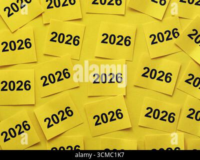 Yellow paper notes with the numbers 2026 on them stuck to a yellow background. Close up. Stock Photo