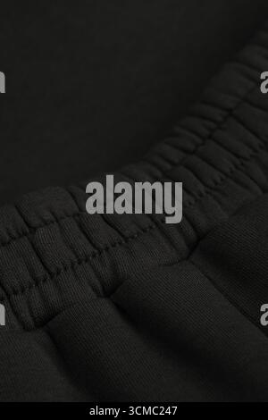 Warm dark khaki tracksuit. Close-up of elastic waistband. Macro of black warm textile fabric. Cotton. Stock Photo
