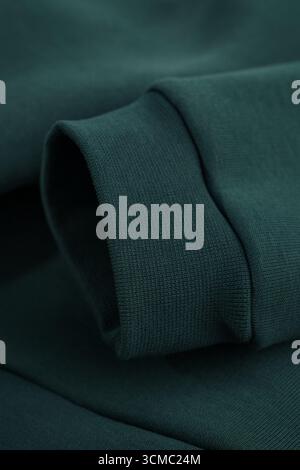 Hoodie texture. Close-up of dark green sweatshirt sleeve. Textile warm fabric macro background. Cotton. Stock Photo