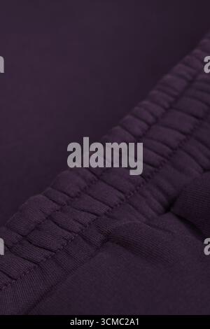 Warm dark purple tracksuit. Close-up of elastic waistband. Textile warm fabric macro. Cotton. Stock Photo