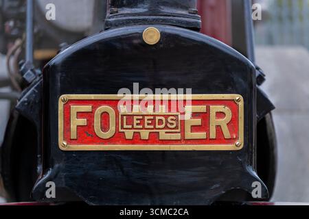 Close-up of cast iron plaque on Fowler steam engine, embossed lettering "FOWLER LEEDS," showcasing industrial craftsmanship. Stock Photo