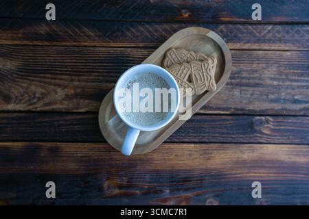 Hot cappuccino served with cookies on a wooden tray. A cozy coffee break on rustic wood background. Stock Photo